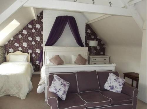a bedroom with a bed and a couch with pillows at Meath Arms Country Inn in Aughrim
