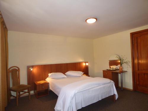 a bedroom with a white bed and a chair at Gura Padurii in Sinaia