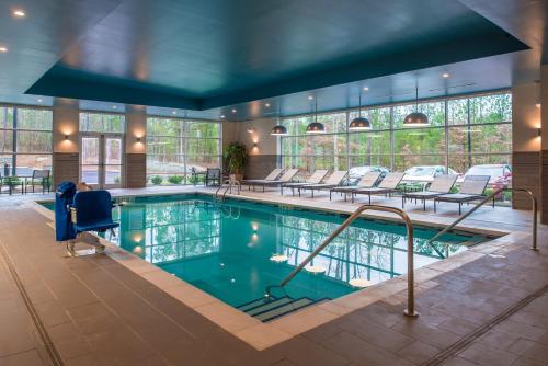 uma grande piscina com cadeiras e mesas num edifício em Hyatt House Raleigh/Rdu/Brier Creek em Raleigh