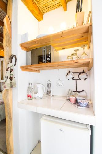 a kitchen with white countertops and wooden shelves at TNiqua Stable Inn in Plettenberg Bay