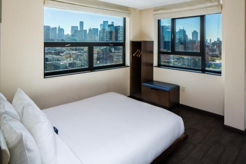 a bedroom with a white bed and large windows at Orchard Street Hotel in New York