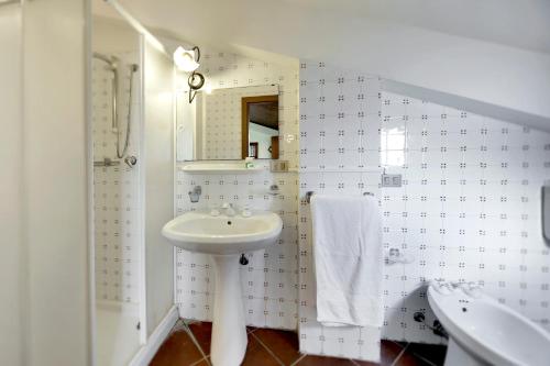 ein weißes Badezimmer mit einem Waschbecken und einem Spiegel in der Unterkunft Villa dell'Ulivo in Marina di Ragusa