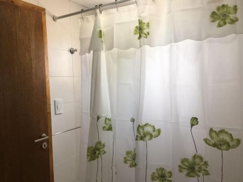 baño con cortina de ducha con flores verdes en Complejo Rafina Villa Gesell en Villa Gesell