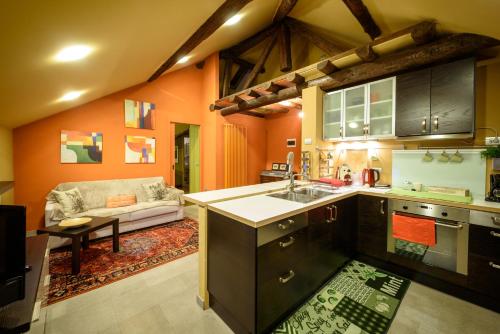 a kitchen with orange walls and a couch in a room at Eco Rooms&Breakfast Tirano in Tirano