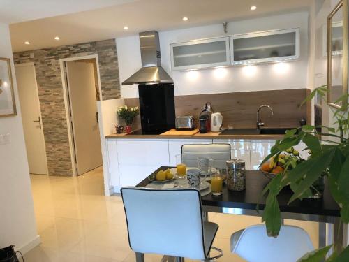 a kitchen with a table and two white chairs at Appartement Cosy Calme Central-Terrasse Proche Palais in Cannes