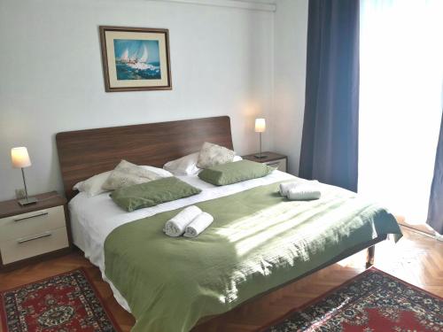 1 dormitorio con 1 cama grande con sábanas y almohadas verdes en Apartments Ogrin, en Portorož