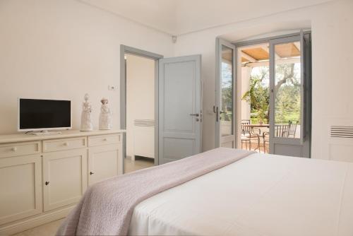 a white bedroom with a bed and a television at Masseria Spesseto in Montalbano