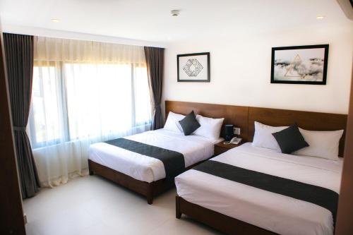 a hotel room with two beds and a window at Robin Hotel Danang in Da Nang
