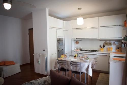 une cuisine avec des placards blancs et une table avec des chaises dans l'établissement Casa Menhir AeT, à Bari Palese