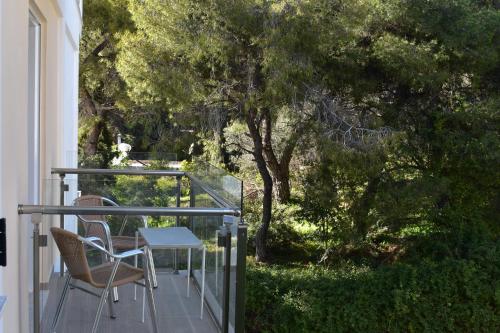 a table and chairs on a balcony with trees at New Aegli Resort Hotel in Poros
