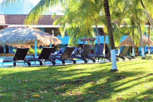 a row of chairs in a park next to a pool at Beach Break Resort & CR Surf Camp in Jacó
