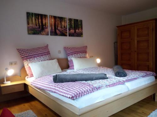 uma cama num quarto com duas pinturas na parede em Ferienwohnung Waldhäusl em Ramsau