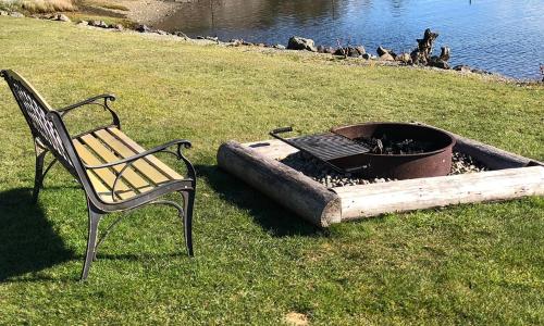 a bench sitting next to a fire pit in the grass at The Waterfront at Potlatch in Shelton