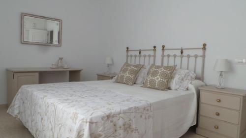 a bedroom with a white bed with pillows and a mirror at Casa mirador in Adeje