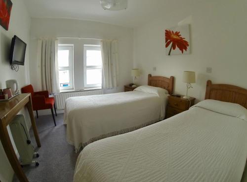 a hotel room with two beds and a television at The Old Anchor B&B Annascaul in Anascaul