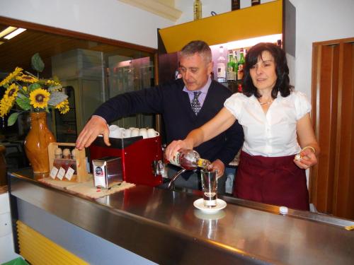 a man and a woman standing at a counter making a drink at Hotel Primavera in Barberino di Val dʼElsa