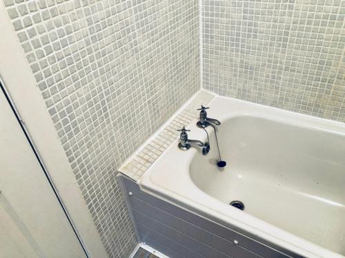 a bathroom with a bath tub with white tiles at Harbour View in Portree