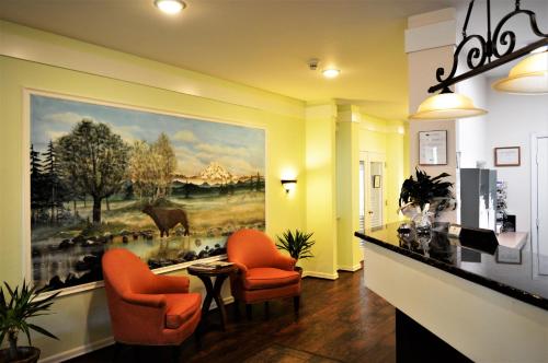 un vestíbulo con sillas naranjas y una pintura en la pared en GuestHouse Inn Enumclaw, en Enumclaw