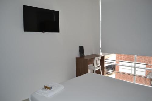 Dormitorio con cama, escritorio y TV en Hotel Grand Premium Plaza en Pitalito