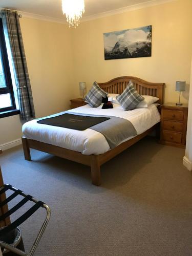 a bedroom with a large bed with a cat sitting on it at Ben Nevis Guest House in Fort William
