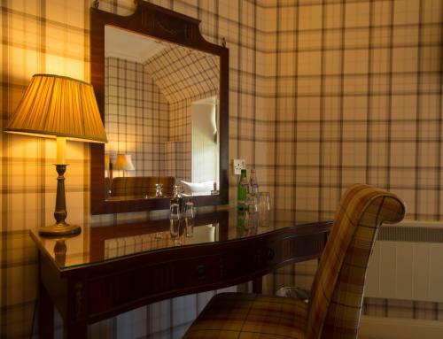 a room with a desk with a lamp and a mirror at The Tongue Hotel in Tongue