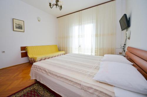 una camera con un grande letto e una sedia gialla di Apartman Nikodem a Novalja (Novaglia)