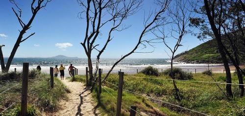 two people walking down a path near the beach at Hat Head Holiday Park in Hat Head