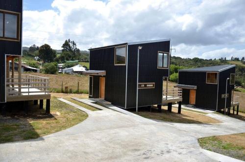 a black tiny house sitting on top of a field at Cabañas Alen Mapu in Castro