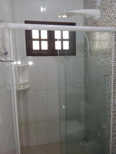 y baño con ducha de cristal y ventana. en Cantinho na Chi'apada, en Lençóis