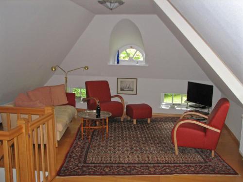 Una sala de estar con sillas rojas y un sofá. en Föhrer Friesenkate Ost, en Nieblum