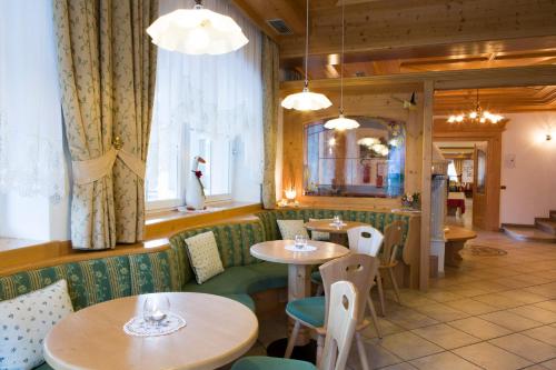 a restaurant with tables and chairs and a window at Hotel Chalet Sas Morin in Pozza di Fassa