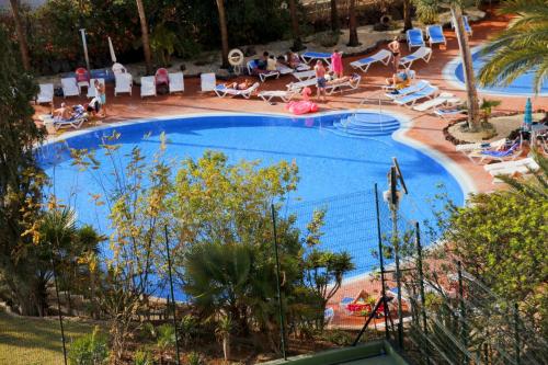 a large blue swimming pool with people sitting in chairs around it at Las Americas Tenerife in Playa de las Americas