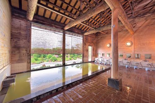 uma grande piscina interior num edifício com uma grande janela em Onsen Yupopo em Senboku