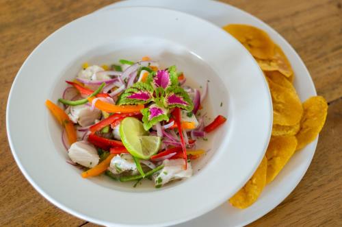 a white bowl of salad with vegetables on a table at Aaki Hotel in Las Peñitas
