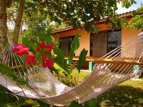 a hammock in front of a house with flowers at Fidelito Ranch & Lodge in Tambor