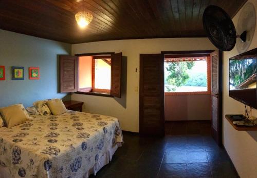 a bedroom with a bed and two windows and a television at Pousada Canto do Rio in Prado