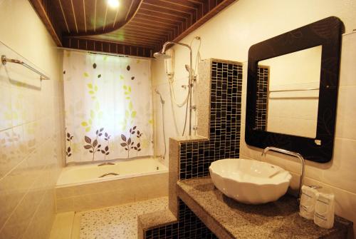 a bathroom with a sink and a shower and a mirror at Nature Beach Resort, Koh Lanta in Ko Lanta