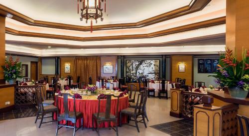 a dining room with tables and chairs and a chandelier at Bayview Hotel Langkawi in Kuah