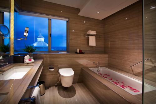 a bathroom with a tub and a toilet and a window at Ascott Waterplace Surabaya in Surabaya