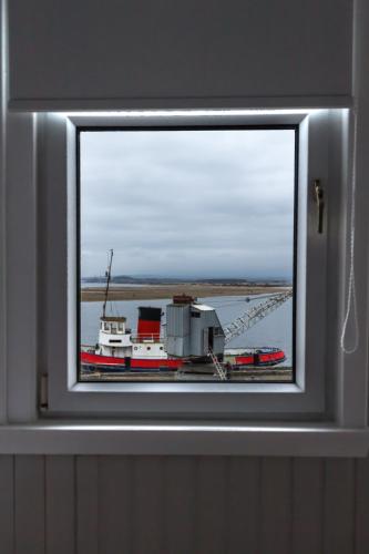 a window in a wall with a boat in the water at Harbourlights Accomodation in Irvine