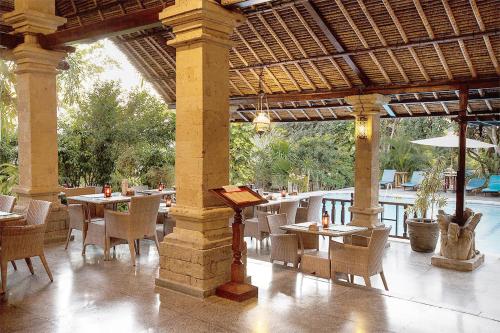 a pavilion with tables and chairs and a patio at Bali Agung Village - CHSE Certified in Seminyak