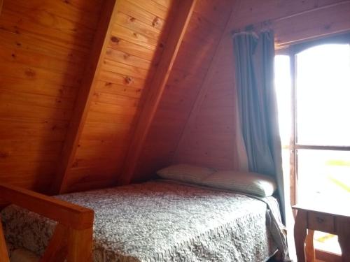 a bedroom with a bed in a wooden cabin at Cabañas Namuncura in Colón