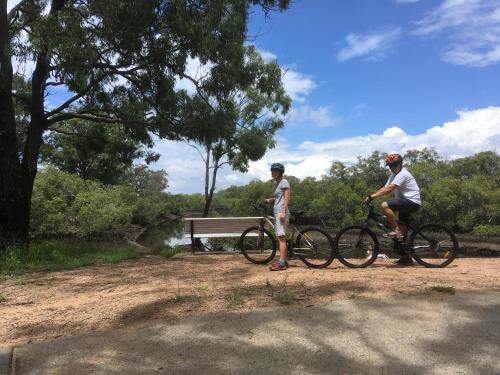 two men riding bikes next to a park bench at Absolute Waterfront in Brisbane