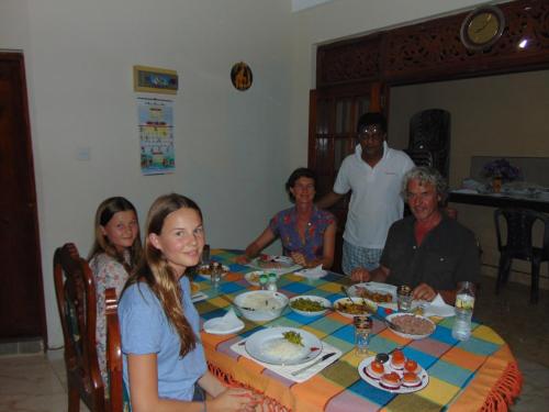 a group of people sitting around a table eating food at Innovick Residence in Kandy