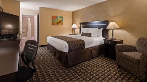 a hotel room with a bed and a chair at Best Western Plus Pleasanton Inn in Pleasanton