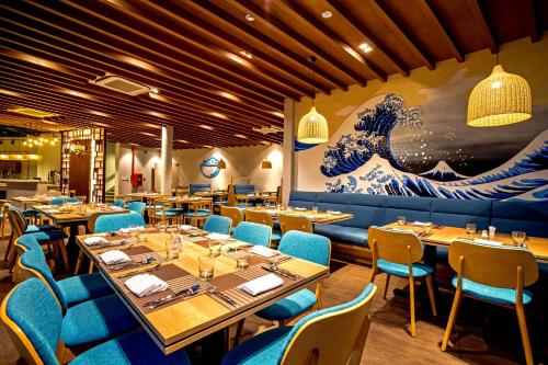 a restaurant with tables and chairs and a large wave mural at Oceanami Villas & Beach Club - Managed by Thang Long Group in Long Hai