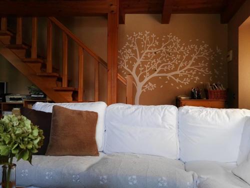 a white couch with a tree stencil on a wall at il Battito in Saint Vincent