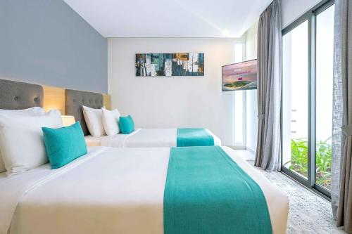 a hotel room with two beds and a large window at Oceanami Villas & Beach Club - Managed by Thang Long Group in Long Hai