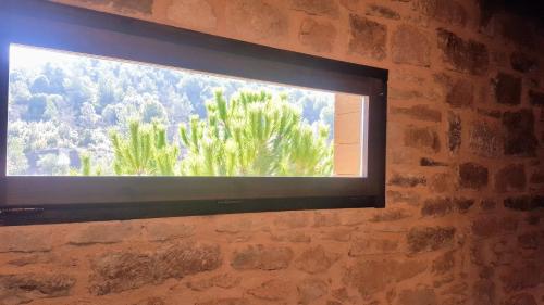 a window in a brick wall with a tree at La Torre Blanca in Cardona