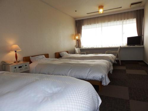 a hotel room with three beds and a window at Itoen Hotel Toi in Izu